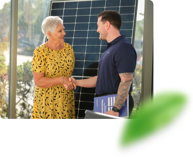 Customer shaking hands with a solar representative after making a decision. There is a solar panel behind them in the background.